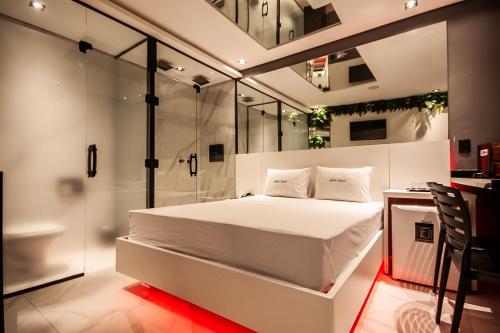 a bedroom with a white bed and a glass wall at Motel Jardim Secreto in Santo André