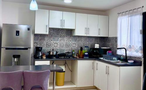 a kitchen with white cabinets and a table and a refrigerator at EXCELENTE ALBERCA PRIVADA EN RESIDENCIAL PRIVADO, GYM, asador in Ciudad Valles