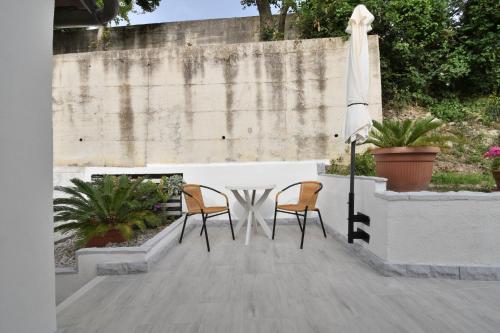 a table with two chairs and a white umbrella at Apartments Plomin in Plomin