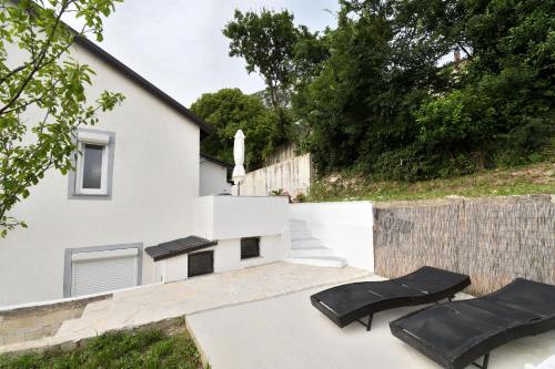 a white house with black chairs and a fence at Apartments Plomin in Plomin