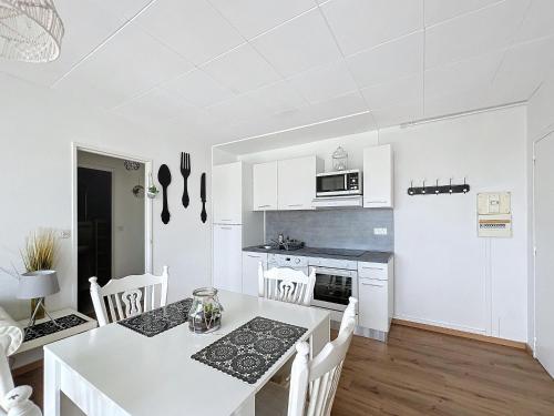 une cuisine blanche avec une table et des chaises blanches dans l'établissement L'air marin, à Ouistreham