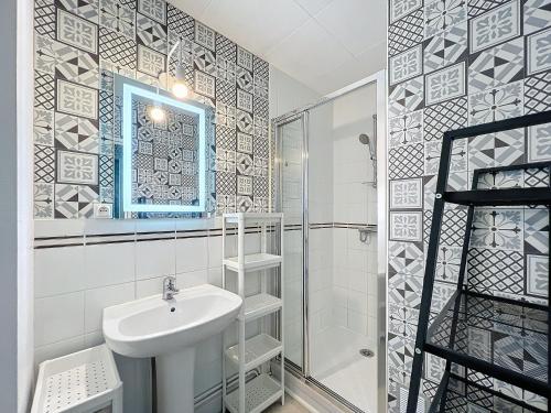 une salle de bain avec un lavabo, une douche et un miroir dans l'établissement L'air marin, à Ouistreham