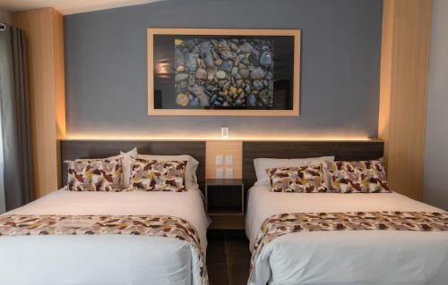 two beds in a room with a painting on the wall at Hotel Esmeralda in Atlixco