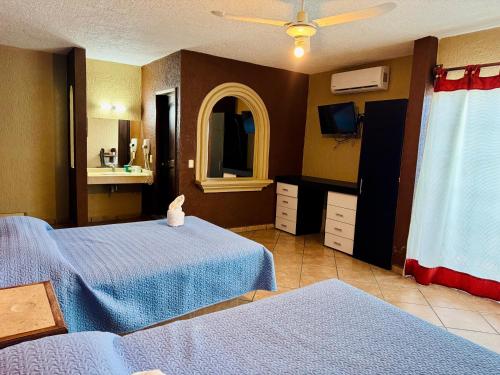 a bedroom with two beds and a mirror and a tv at Hotel Cabañas Santa Cruz in Oaxtepec