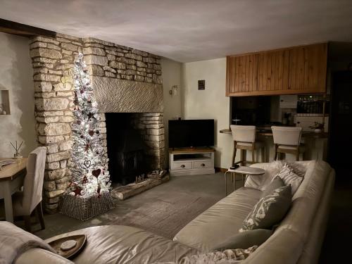 a living room with a christmas tree in front of a fireplace at Cupcake Cottage: Quintessential Cotswold Cottage in Nailsworth
