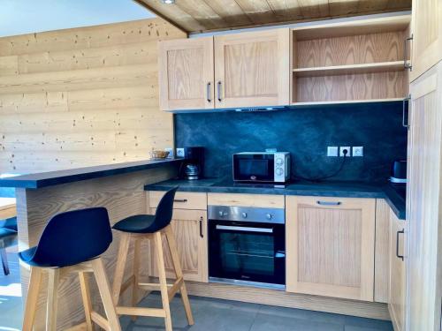 - une cuisine avec des placards en bois, 2 chaises et un four micro-ondes dans l'établissement La Residence - Appartement La Résidence MAE-9481, à Vénosc
