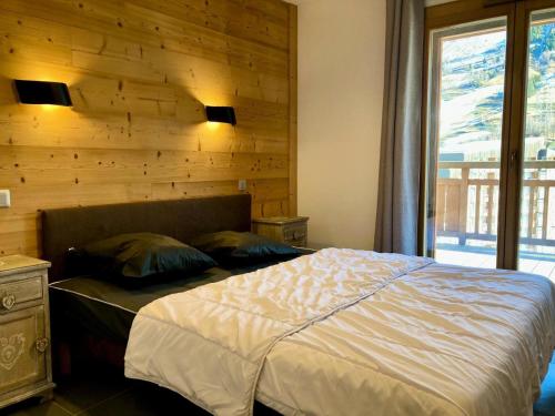 - une chambre avec un lit et un mur en bois dans l'établissement La Residence - Appartement La Résidence MAE-9481, à Vénosc