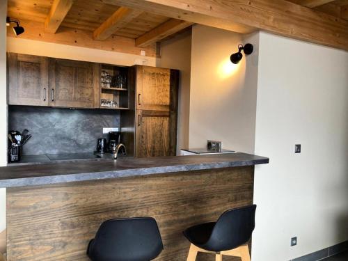 une cuisine avec un bar avec deux chaises noires dans l'établissement La Residence - Appartement La Résidence MAE-9501, à Vénosc