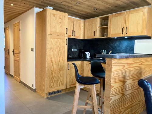 une cuisine avec des placards en bois et un comptoir avec deux chaises dans l'établissement La Residence - Appartement La Résidence MAE-9701, à Vénosc