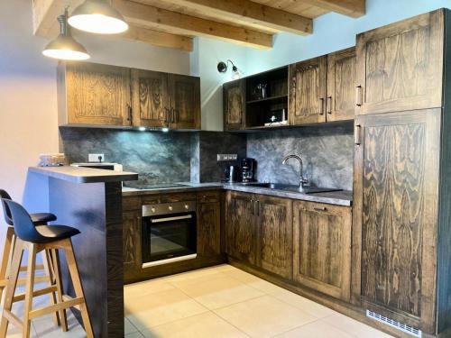 - une cuisine avec des placards en bois, un évier et un tabouret dans l'établissement La Residence - Appartement La Résidence MAE-9711, à Vénosc