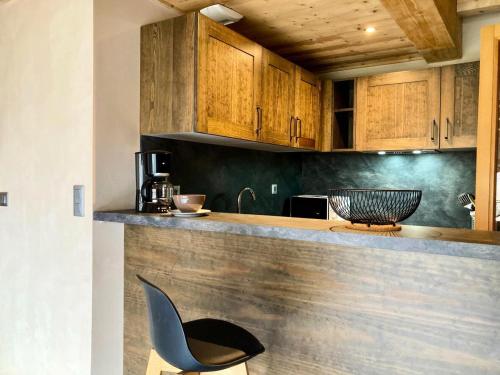 une cuisine avec des placards en bois et une chaise noire dans l'établissement La Residence - Appartement La Résidence MAE-9721, à Vénosc