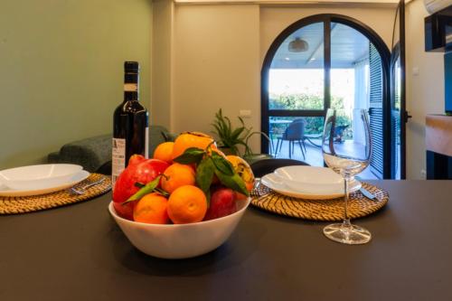 a bowl of fruit on a table with a bottle of wine at HOLIDAYS HOMES ROME GOLF Appartamenti Marco Simone AeB in Marco Simone