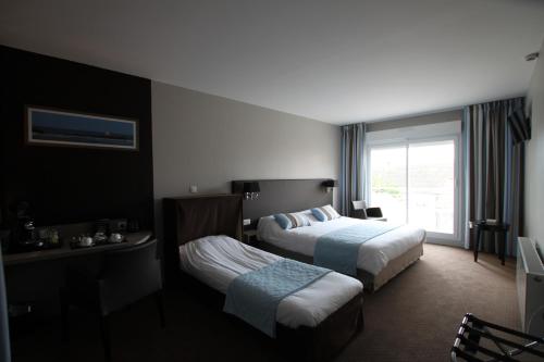 a hotel room with two beds and a window at Hôtel Le Cheval Blanc in Quend-Plage