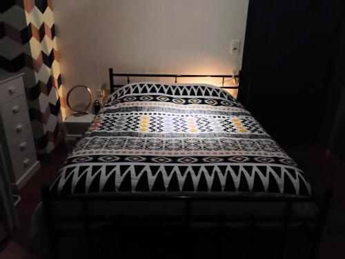 a bed with a black and white comforter on it at Gîte avec parking, au calme, entre Colmar-Riquewihr et Obernai ,marchés de Noël, 3 chambres, avec terrasse in Châtenois
