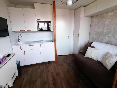un petit salon avec un canapé et une cuisine dans l'établissement Résidence Le Chanteloup - Studio fonctionnel pied des pistes MAE-9431, à Aime La Plagne