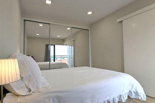 a bedroom with a white bed and a large mirror at Top-Floor One-Bedroom Flats - Peaceful with Ocean and City Views in Funchal
