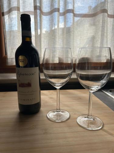a bottle of wine and two wine glasses on a table at Casa dei pazzi Montanari da Cristina in Alfedena