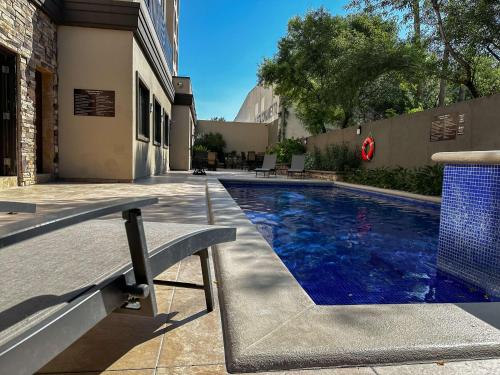 a swimming pool with a bench next to a building at Best Western PREMIER Monterrey Aeropuerto in Monterrey