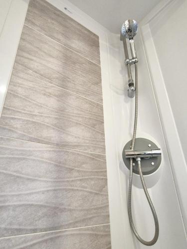 a shower in a bathroom with a gray tile floor at Whitstable Pearl - Alberta Holiday Park in Seasalter