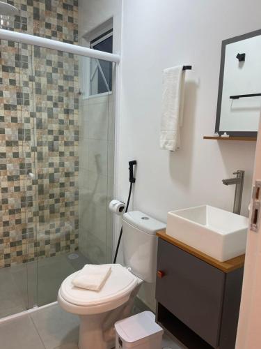 a bathroom with a toilet and a sink and a shower at Hotel Rosa da Ilha Guaruja - 80m do mar, 02 piscinas, sala de jogos, brinquedão de percurso para crianças in Guarujá