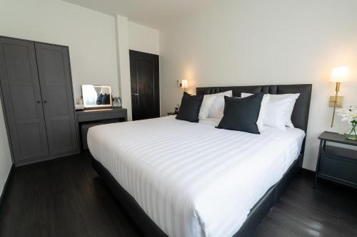 a bedroom with a large white bed with black pillows at House 158 Patong Pool Villa 4BR Near Beach in Patong Beach