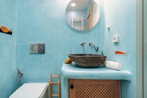 a bathroom with a bowl sink on a blue wall at Aethrion Boutique Apartment in Naxos Chora