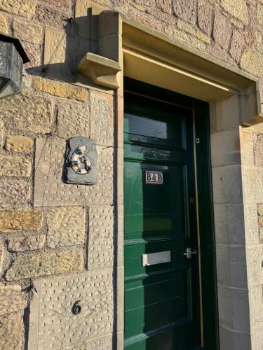 eine grüne Tür in einem Steingebäude mit Ziegelwand in der Unterkunft Ford Village Bed & Breakfast in Ford