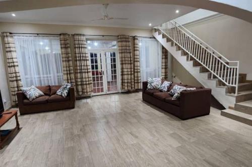 a living room with two couches and a staircase at Asante Beach Villa in Chimpamba