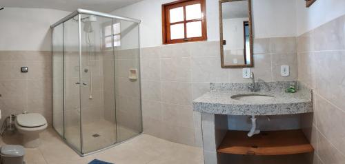 a bathroom with a shower and a sink and a toilet at Fazenda Pousada Cachoeira do Flávio in São Thomé das Letras