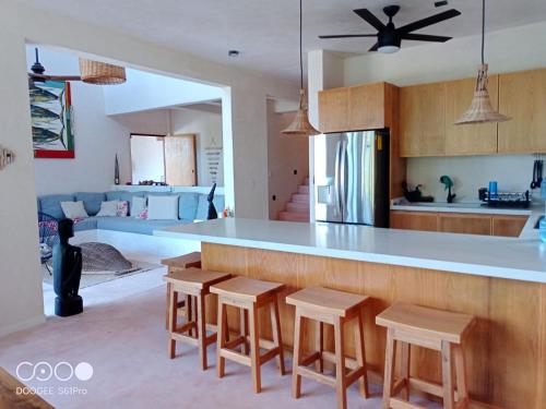 a kitchen with a bar with stools and a counter top at Villa Queridoro Mahahual in Mahahual