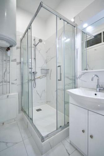 une salle de bain blanche avec une douche et un lavabo dans l'établissement Le Magenta - Coeur de Paris - Canal Saint Martin - 3 Chambres 6 personnes, à Paris