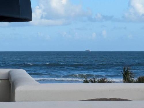 a white couch sitting next to the ocean at Oceanfront 2br2b, Ocean Views, Heated Pool, Spa in Cape Canaveral
