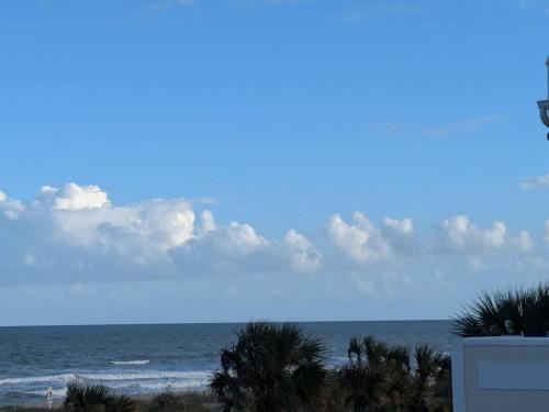 a view of the beach with palm trees and the ocean at Oceanfront 2br2b, Ocean Views, Heated Pool, Spa in Cape Canaveral