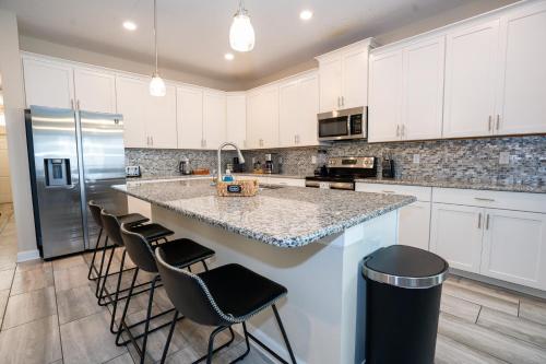 a kitchen with white cabinets and a island with bar stools at Storey Lake Pool Home with Resort Amenities near DISNEY in Kissimmee