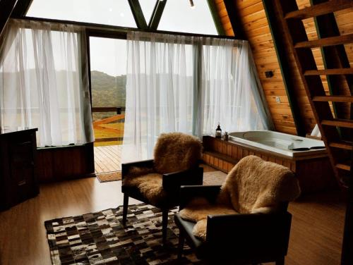 a living room with a tub and two chairs at Chalés Corucacas in Cambará