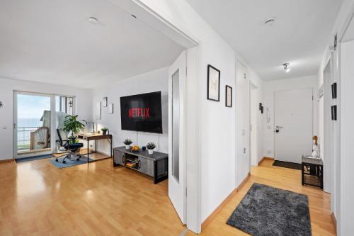 a living room with white walls and a television on a wall at Strand-Apartment, Strandkorb, Meeresrauschen, Parkplatz in Wilhelmshaven