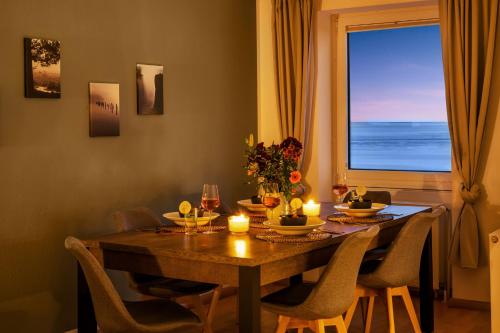 a dining room table with candles and a large window at Strand-Apartment, Strandkorb, Meeresrauschen, Parkplatz in Wilhelmshaven