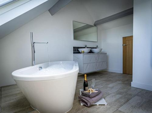 a white bathroom with a tub and a sink at Long Barn, seaside cosy cottage for 8 in Beaumaris