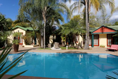 a swimming pool in front of a house with palm trees at Minen Hotel in Tsumeb