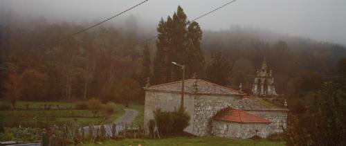 a small building in a field with a road in the background at Xanela Xures in Muiños
