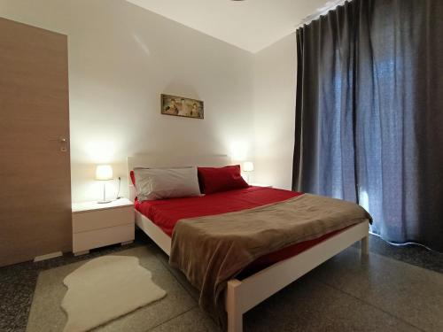 a bedroom with a bed with red sheets and two lamps at Erika's Home in Milan