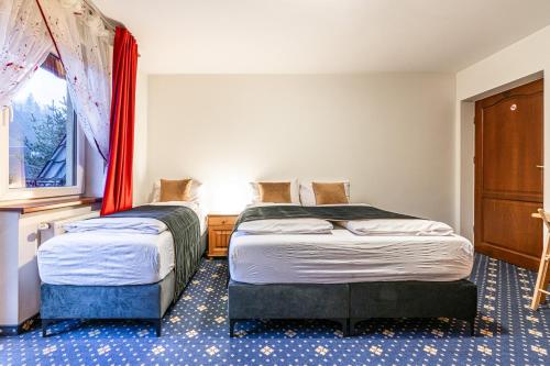 two beds in a room with a window at Dunajecki Dworek in Zakopane