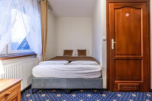a small bedroom with a bed and a wooden door at Dunajecki Dworek in Zakopane