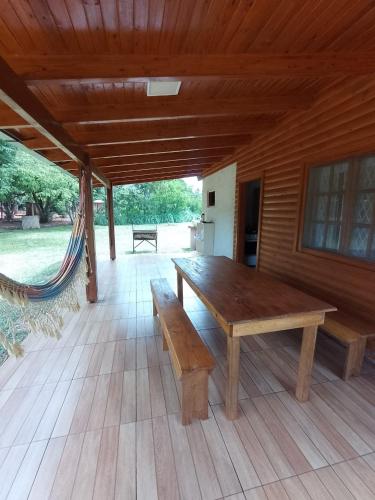 a large wooden bench on a patio with a hammock at Los Lapachos Lodge in Puerto Libertad