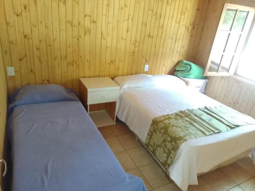 two beds in a room with wooden walls at Los Lapachos Lodge in Puerto Libertad