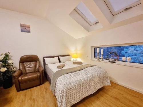 a bedroom with a bed and a chair at Neue Moderne FeWo Europa-Park & Rulantica in Ringsheim