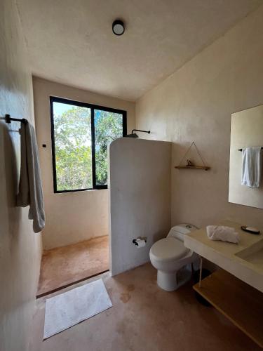 a bathroom with a toilet and a window at Villa Queridoro Mahahual in Mahahual