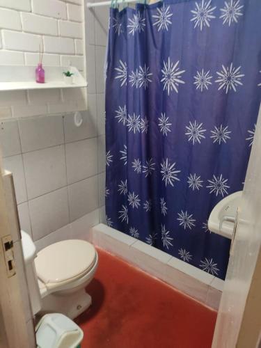 a bathroom with a toilet and a blue shower curtain at Beach House SantaElena in Pisco