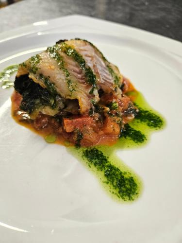 a piece of meat on a white plate with broccoli at Hotel Villa Camilla in Varazze