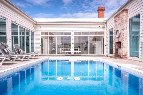 a swimming pool in front of a house at Ocean Beach House Sorrento - Luxury with Heated Pool and Spa in Sorrento